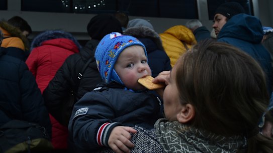 A woman holds her child as other evacuees from Kherson flee the city.