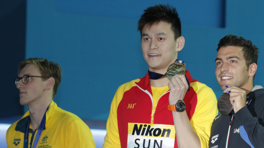 China's Sun Yang, centre, holds up his gold medal with silver medalist Australia's Mack Horton, left, on Sunday.