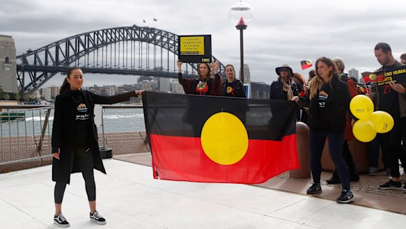 Cheree Toka and fellow demonstrators hold an Aboriginal Flag during a demonstration in Sydney.