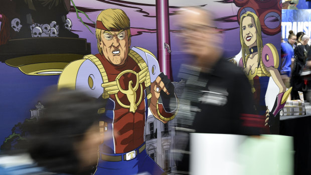 Attendees walk past cut-out figures of President Donald Trump and his daughter Ivanka at a booth for the satirical comic book series "Trump's Titans" in San Diego.