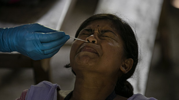 An Indian health worker takes a nasal swab sample of a student at a college in  Jhargaon village, India.