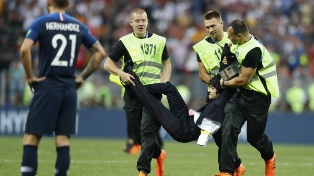 A woman dressed as a police officer is removed from the pitch.