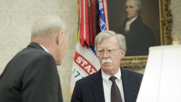 White House Chief of Staff John Kelly, left, talks with, White House National Security Advisor John Bolton, right, in the Oval Office of the White House in Washington.