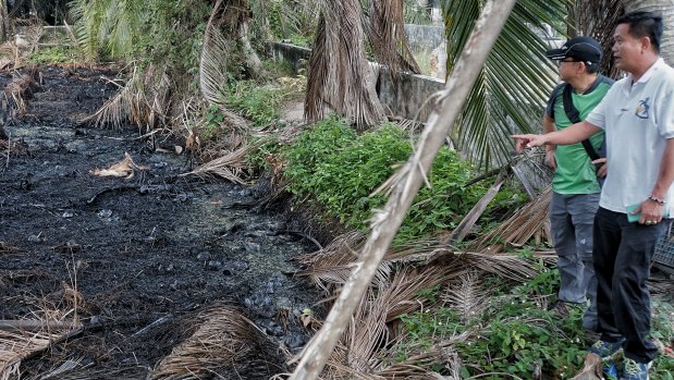 Local NGO members point to the illegal waste dumping site pond in Malaysia.