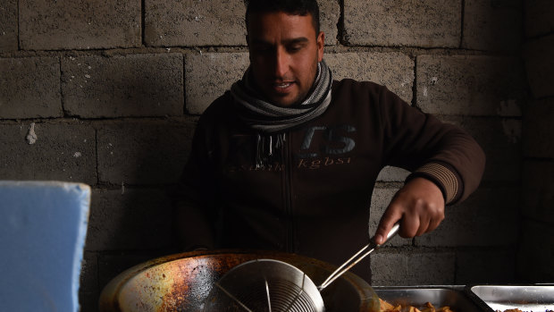 A man fries falafel and chips in hot oil in Daquq IDP camp in Kirkuk, Iraq. 