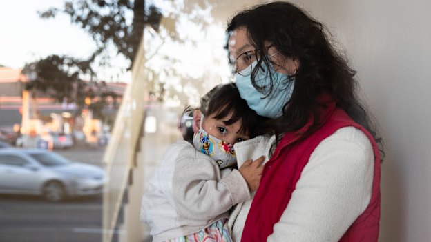 Leidy Castro Meneses with her daughter, Sofia, in the lobby of their Yagoona apartment building. She is relieved to be vaccinated now that the virus is raging in her local area.