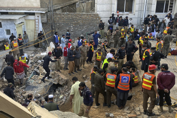 Security officials and rescue workers search bodies at the site of suicide bombing in Peshawar.