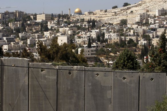 The Dome of the Rock, located on the compound known to Muslims as al-Haram al-Sharif (Noble Sanctuary) and to Jews as Temple Mount in Jerusalem's Old City, is seen in the background above the controversial Israeli barrier in the West Bank village of Abu Dis in September 2009. 