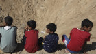 Palestinian children sit at the edge of a crater after an Israeli airstrike in Khan Younis.