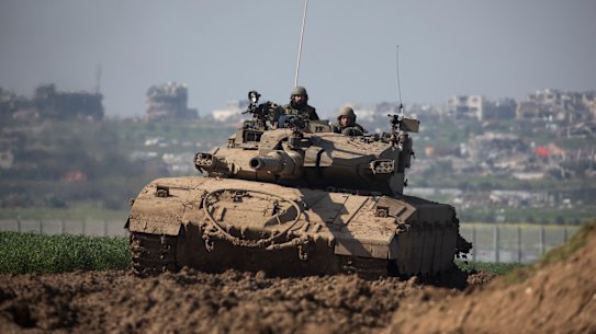 An Israeli tank moves along the border, as Gaza is seen behind in Southern Israel.