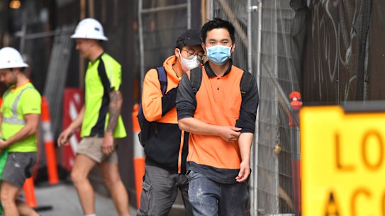 Construction workers in face masks leave a city building site earlier this week.