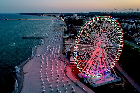 A ferris wheel is illuminated at dusk along the beach on the Baltic Sea in Groemitz, Germany.