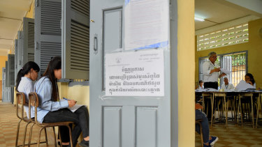 An election official counts the votes from the Cambodian election as two women independently record the count.