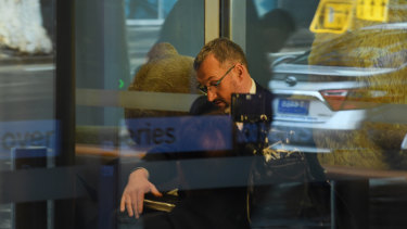One of three AFP officers sits in the reception of the ABC offices in Ultimo