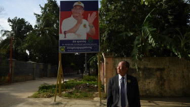 Mam Sonando stands in front of his campaign banner at the Beehive Social Democratic Party headquarters outside Phnom Penh. 