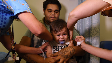 Anthony Dargin, 22, kisses his one-year-old son Ivory after he gets immunisation shots at the Tharawal Aboriginal Corporation Aboriginal Medical Service in Airds.