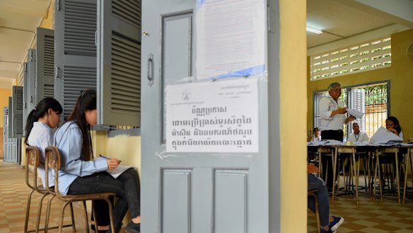 An election official counts the votes from the Cambodian election as two women independently record the count.