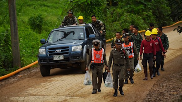 Thai police and military walk towards the cave on Wednesday morning.