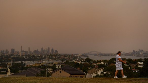 Dust fills the air as a woman walks at Dudley Page Reserve in Dover Heights on Wednesday morning.