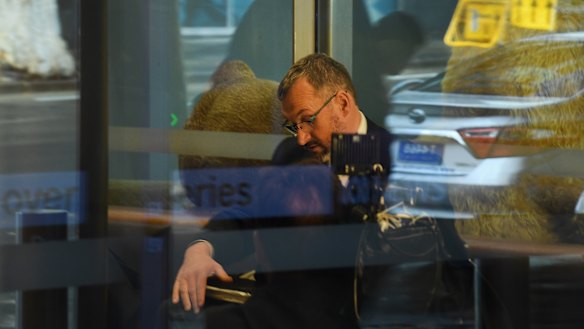 One of three AFP officers sits in the reception of the ABC offices in Ultimo