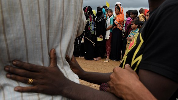 Rohingya women queue at a distribution site after the downpour.