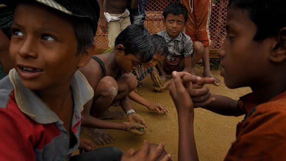 Rohingya children play in the mud with marbles in Kutupalong refugee camp after a monsoonal downpour.