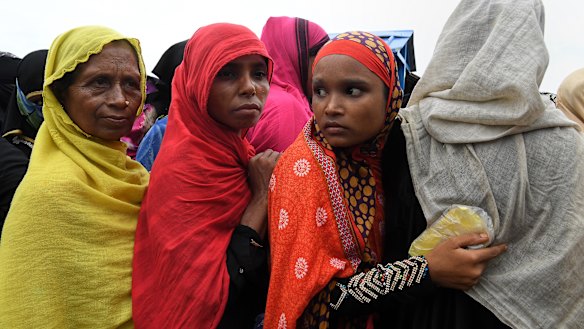 A Rohingya woman holds her ration cards in a plastic cover to protect them from the rain whilst in queuing for food.