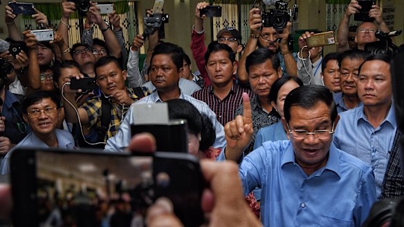 President of the Cambodian People’s Party Hun Sen raises his finger indicating he has voted.