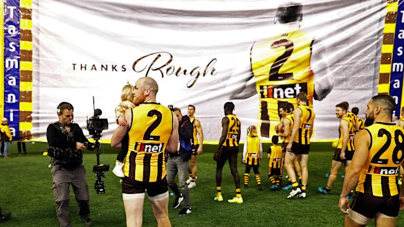 Memorable exit: Jarryd Roughead of the Hawks carries his daughter Pippa through the banner before the game against Gold Coast.