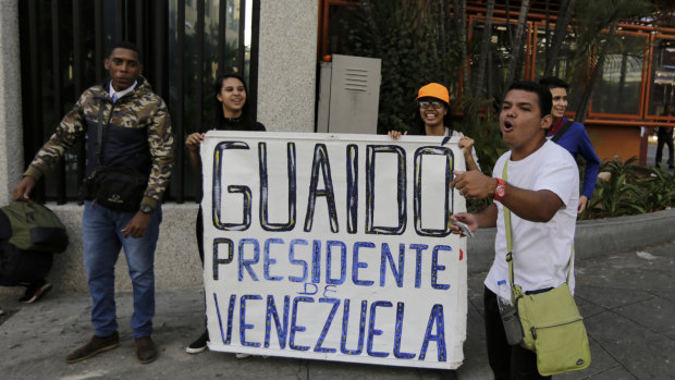 Anti-government protesters show a sign that reads in Spanish "Guaido President of Venezuela" after a rally demanding the resignation of President Nicolas Maduro in Caracas, Venezuela.