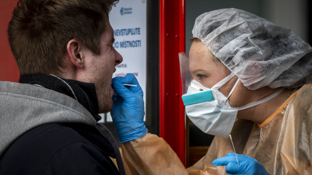 A medical worker takes a sample to test a possible patient infected with coronavirus at a mobile testing centre in Prague, Czech Republic. 