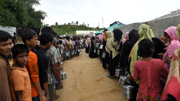 Rohingya refugees queue for a meal provided by a Turkish aid agency at a food distribution site in Shofiullah Kata Camp in Bangladesh.