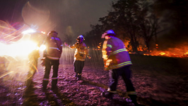 Firefighter Mikaela Kremer dances to celebrate the sudden burst of rain over  Glenbrook-Lapstone bringing a welcome relief from the fires on Saturday, December 21, 2019.
