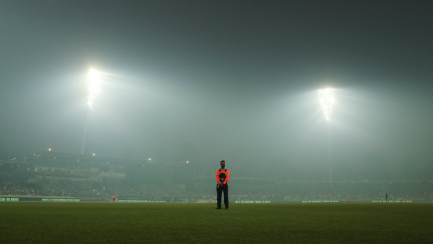 A security guard stands sentry amid the haze at Manuka Oval.
