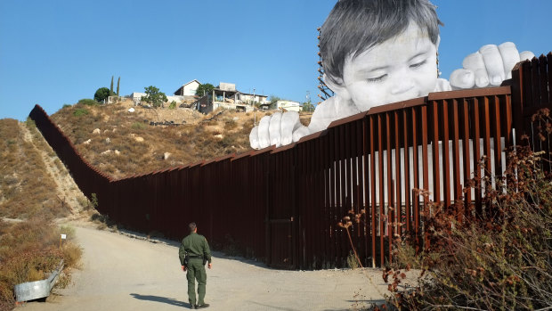 JR's 21-metre-high installation of a child, "Kikito", peers over the wall that partitions Mexico from the US.
