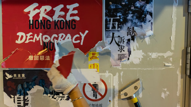A pro-China supporter cleans up a Lennon walls of anti-government posters and memo notes outside Yeun Long MTR station on Saturday. 