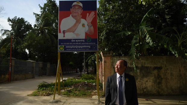 Mam Sonando stands in front of his campaign banner at the Beehive Social Democratic Party headquarters outside Phnom Penh. 