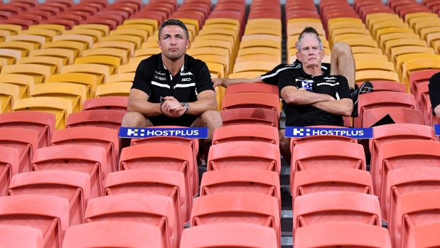 Sam Burgess, left, and Rabbitohs coach Wayne Bennett watching the game unfold from behind the goal posts.