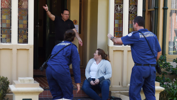 A volunteer imitates an angry person while NSW paramedics assist another volunteer posing as a patient.