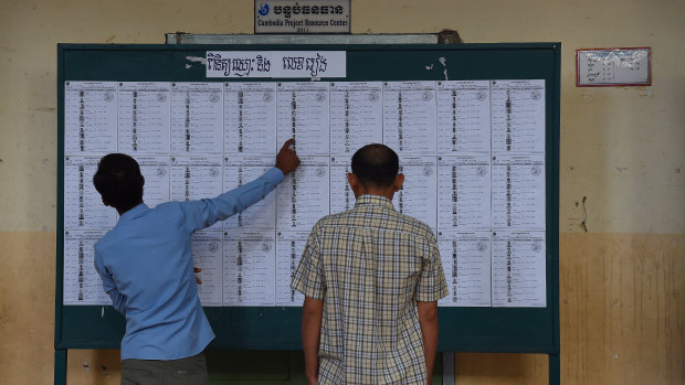 Cambodian men search for their names on the voter lists during the  election at Kandal Provincial Teacher Training School.