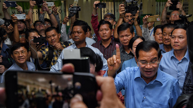 President of the Cambodian People’s Party Hun Sen raises his finger indicating he has voted.