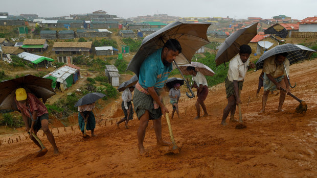 A group of men work in the rain to create drainage on the side of a cliff in preparation for overdue monsoon rains.