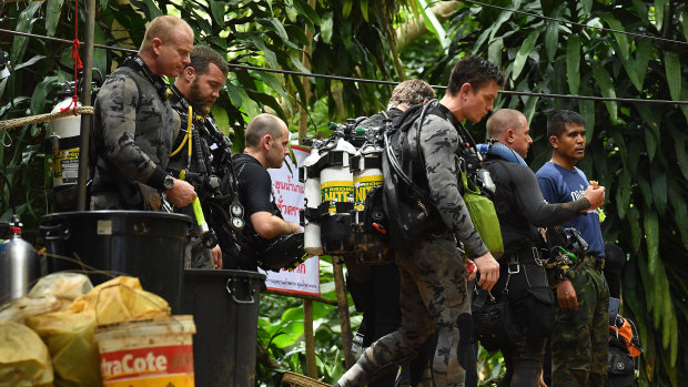 Members of the Australian Federal Police dive team walk down the track that leads to the cave entrance where the rescue operations are being planned.