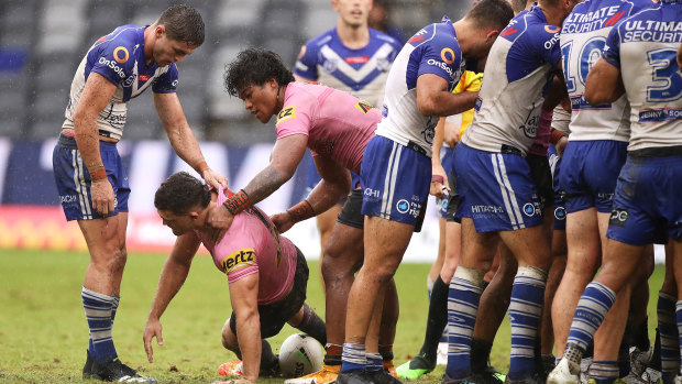 Nathan Cleary is helped to his feet after a careless high tackle by Dallin Watene-Zelezniak of the Bulldogs.