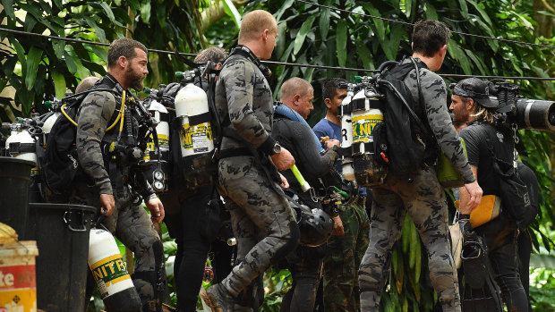 Members of the Australian dive team walk down the track that leads to the cave entrance where the rescue operations are being planned for the 12 boys and their soccer coach who have been trapped inside Tham Luang cave.