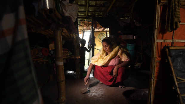 Rohingya refugee Asmida Khatun, 30, smooths out cement on the floor of her family’s shelter.