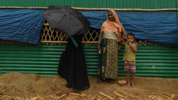 Rohingya women take shelter during a monsoonal downpour in Hakim Para Camp this week.