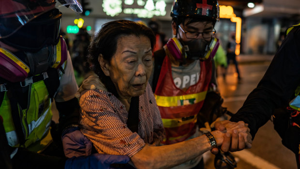 Volunteer medics help a woman cross a road during a clash between police and protesters in Causeway Bay district in Hong Kong.