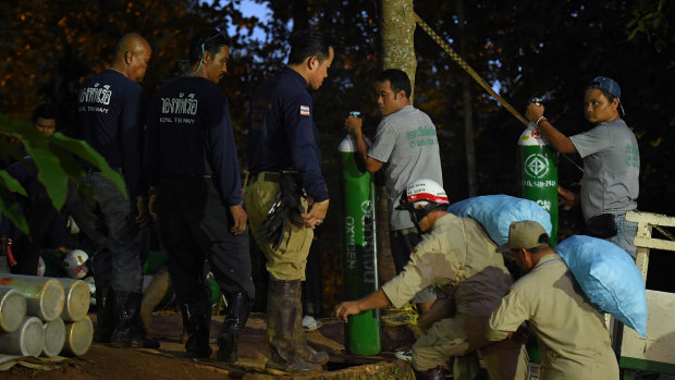 Rescuers move extra supplies of oxygen near the cave on Thursday.