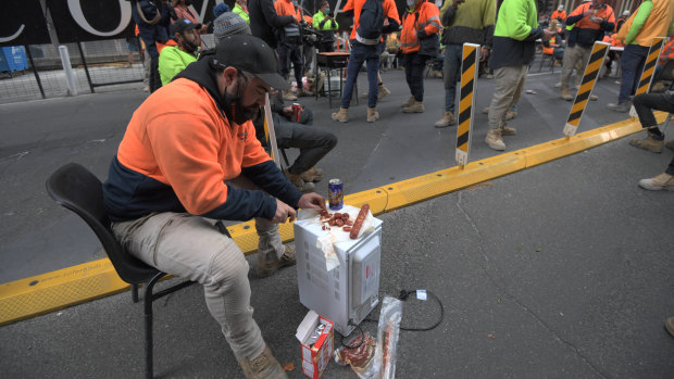 A worker cuts up salami on Lonsdale Street to share with his colleagues. 